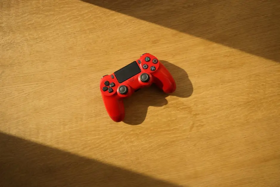 A vibrant red gaming controller placed on a sunlit wooden surface, viewed from above.