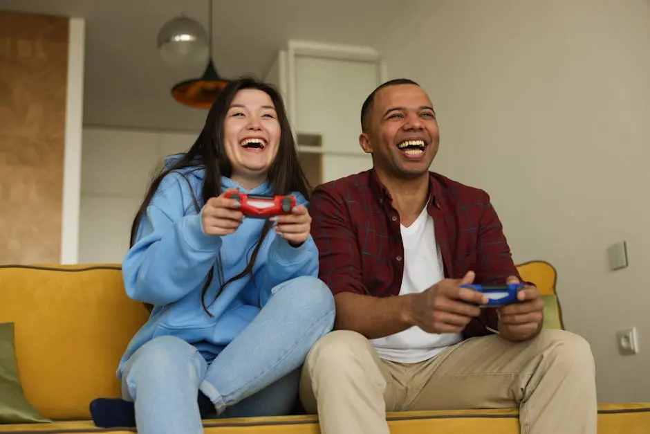 Cheerful interracial couple having fun playing video games on a sofa, showcasing happiness and technology.