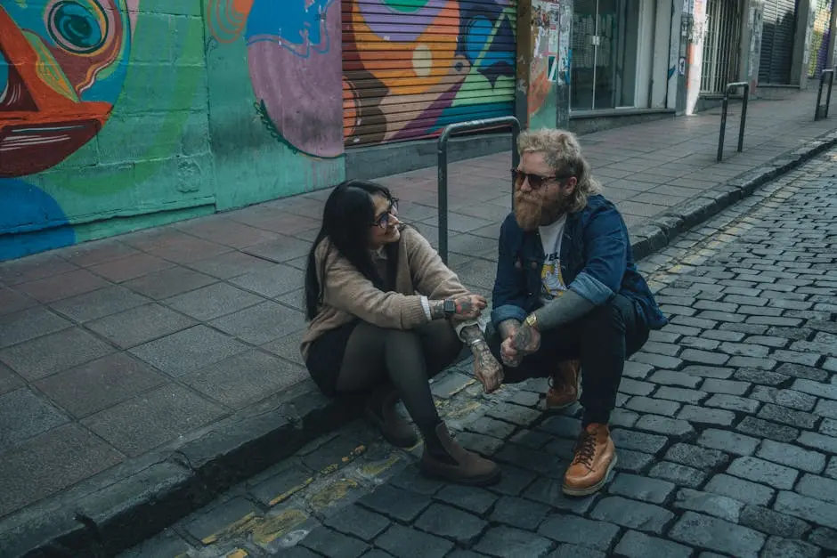 Stylish couple with tattoos chatting on graffiti-lined street.