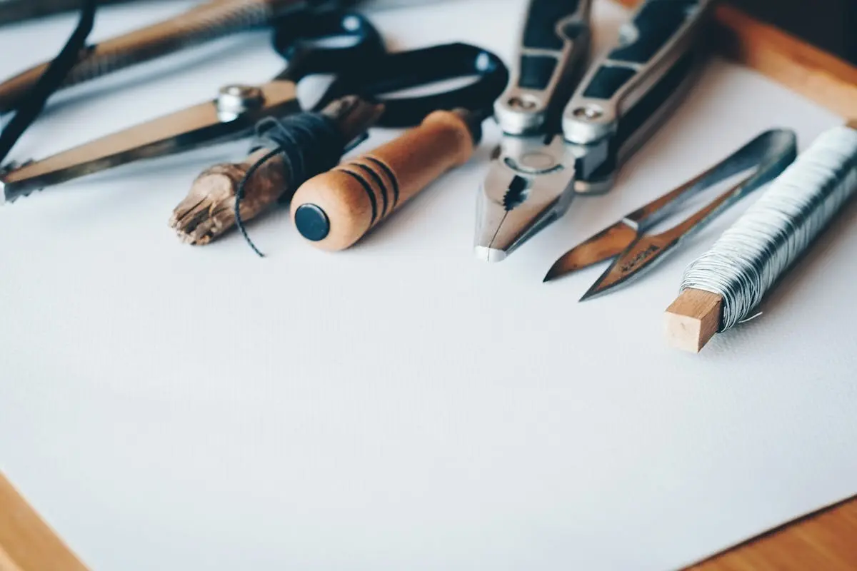 A selection of artisan tools and handmade crafts displayed on a white desk, perfect for online course