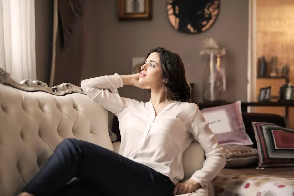 A serene woman enjoys a moment of reflection on a luxurious vintage sofa in a well-designed interior.