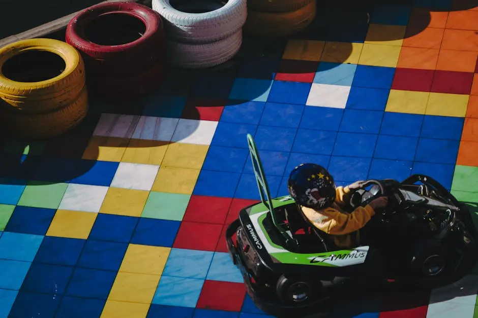 Child in go-kart racing on colorfully tiled track surrounded by tires.