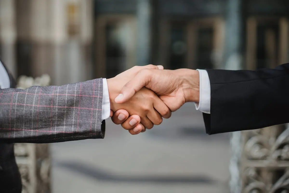 A close-up of two businesspeople shaking hands, symbolizing cooperation and partnership. How to Buy a Small Business