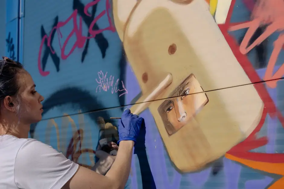 A woman artist paints a colorful mural on an outdoor urban wall.
