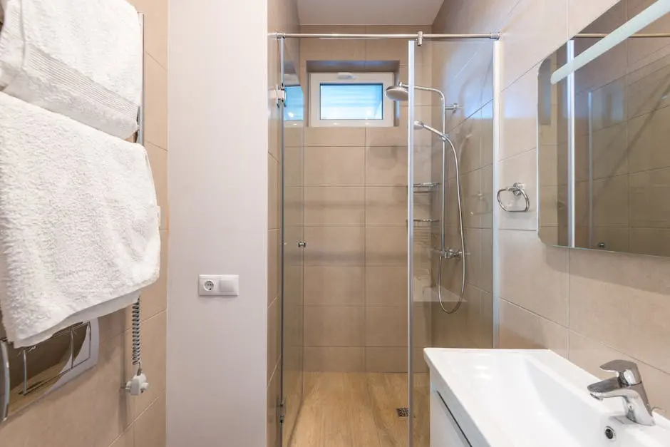 Contemporary bathroom featuring a glass shower, beige tiles, and a sleek sink area.