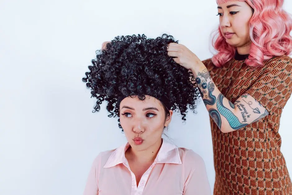 A hairstylist with tattoos fits a curly black wig on a woman in a salon.