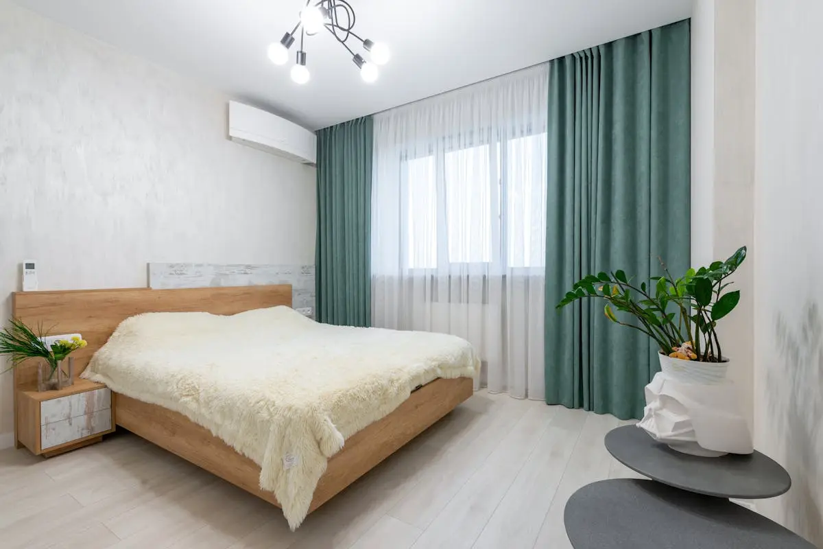 Bright and minimalist bedroom featuring a modern design with wooden elements and green curtains.