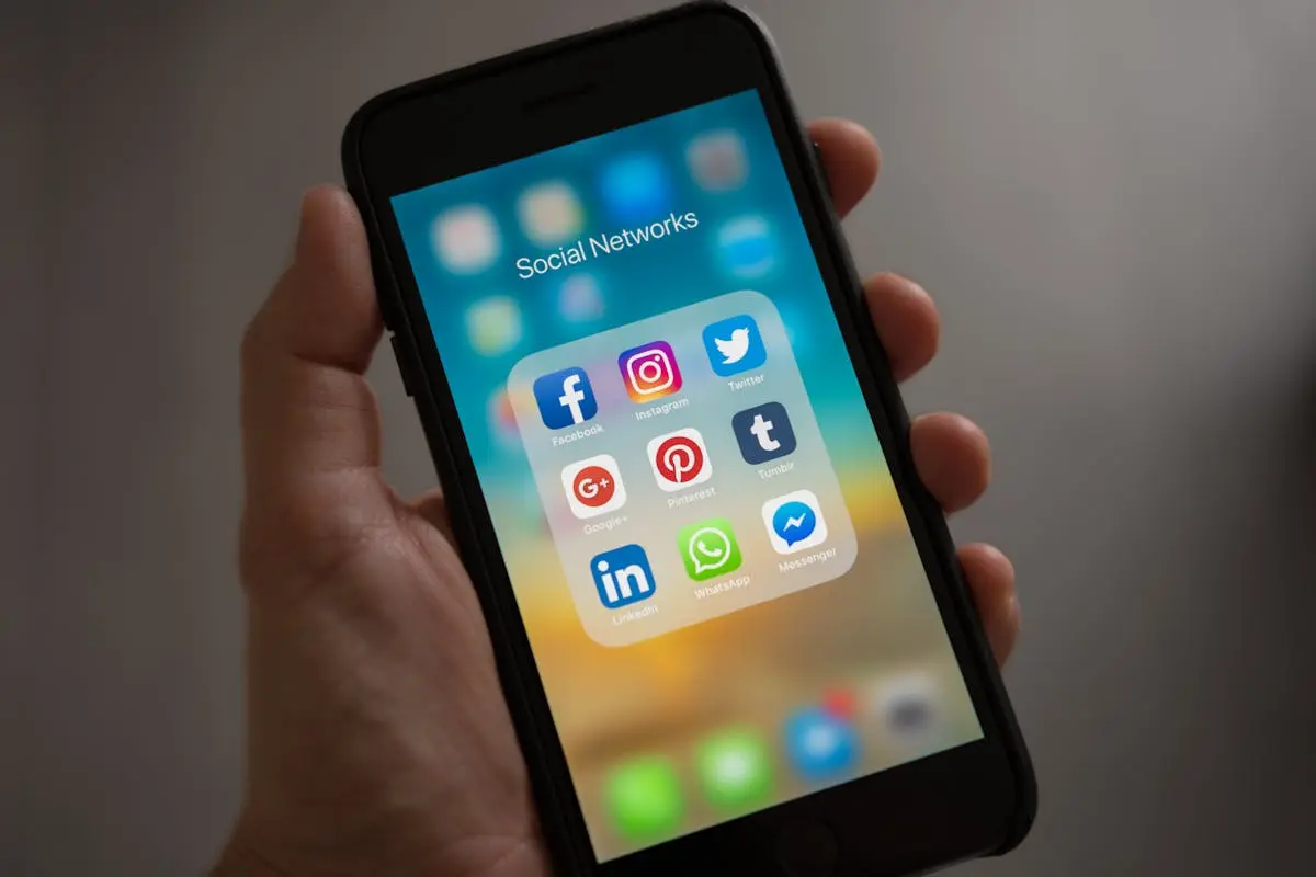A smartphone displaying various social media icons held in a hand, showcasing modern communication apps. prompts