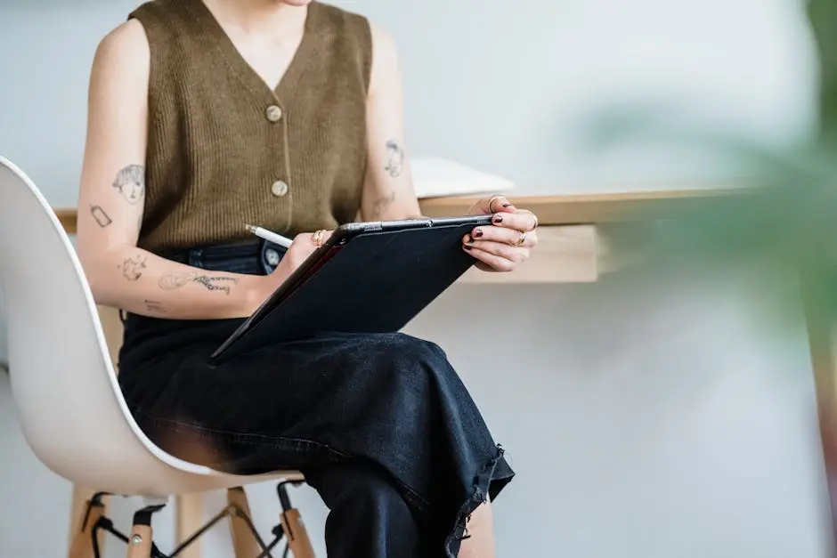 A woman sitting in a chair using a tablet for digital drawing indoors, showcasing creativity and modern design.