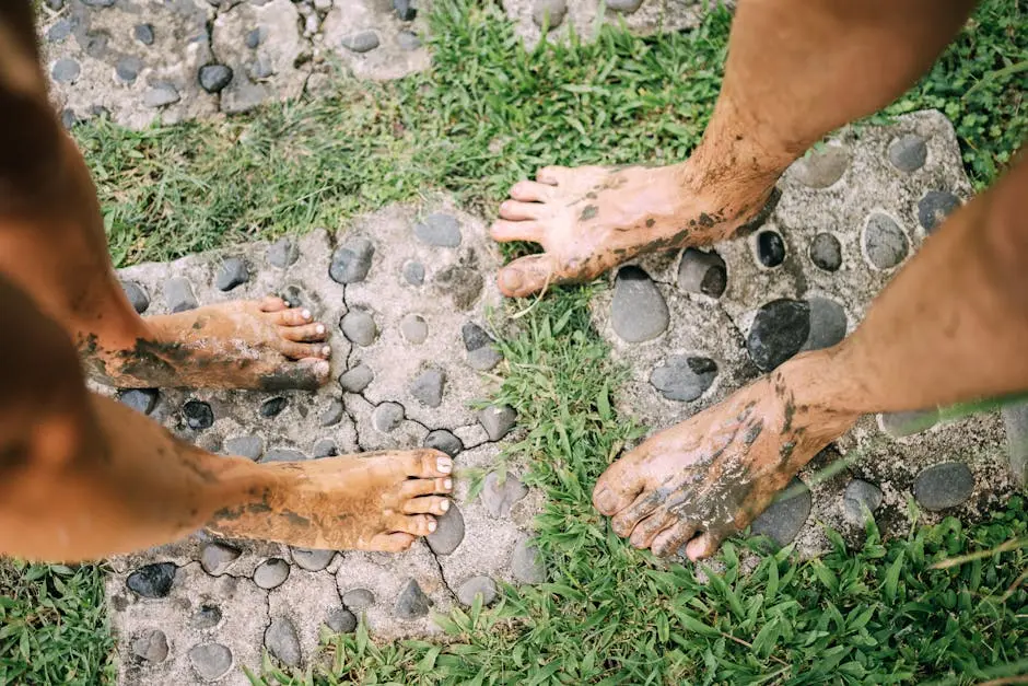 Two adults with muddy feet on a stone path enjoying an outdoor experience.