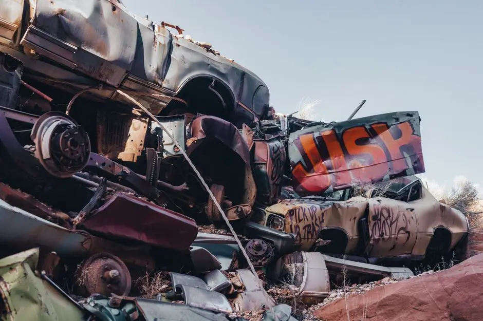 A pile of old, rusty cars stacked haphazardly in an outdoor junkyard.