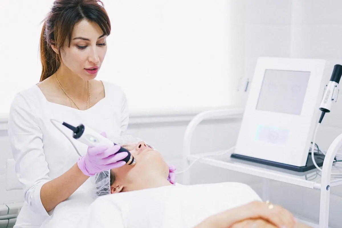 Aesthetician providing a laser facial treatment to a patient in a spa clinic setting.