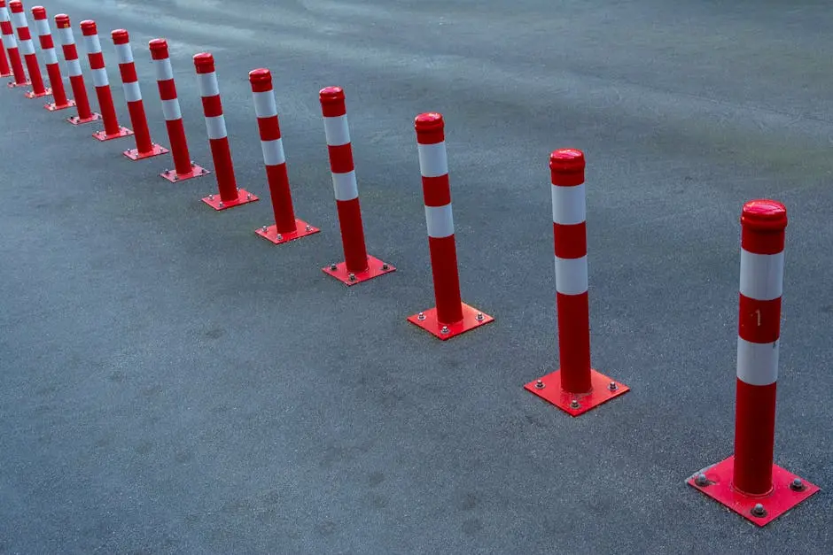 Line of red and white bollards on asphalt road for traffic control and safety.