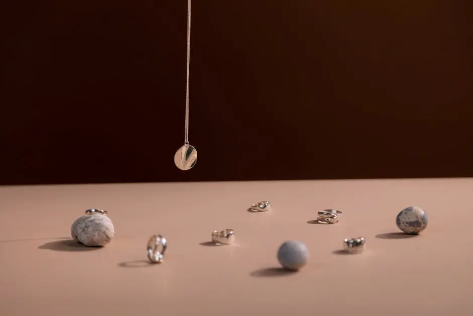 Elegant still life featuring silver jewelry with gemstones on a beige surface.