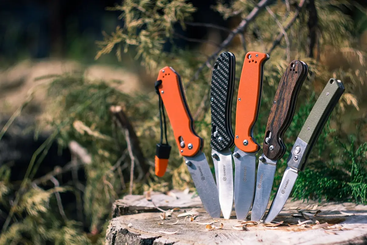 A collection of stylish pocket knives displayed outdoors on a tree stump.