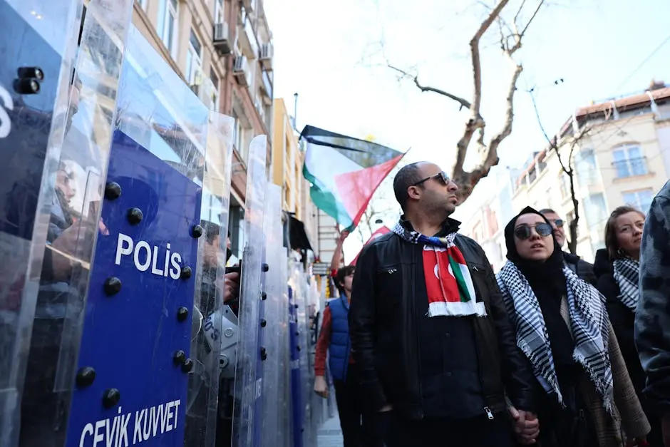 Crowd of protesters in Istanbul with police barriers and flags.