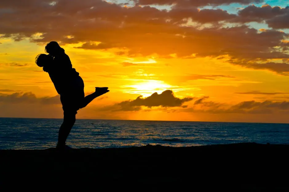 Silhouette of a romantic couple embracing on a beach at sunset, showcasing love and tranquility.