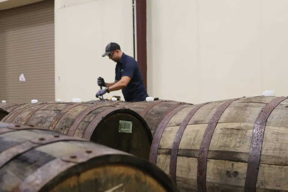 A worker carefully inspecting wooden barrels in a winery room, ensuring quality.
