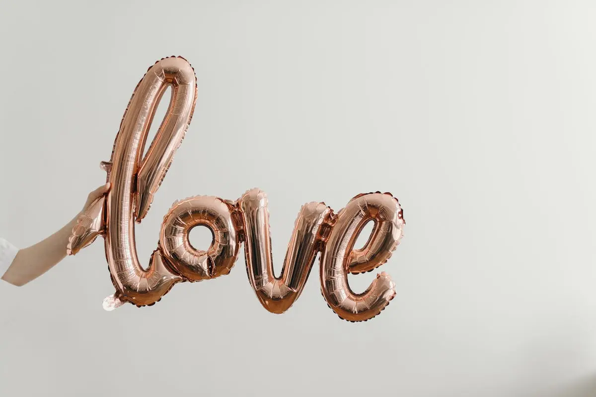 Elegant rose gold balloon spelling ‘love’ on a soft background, perfect for Valentine’s Day themes.