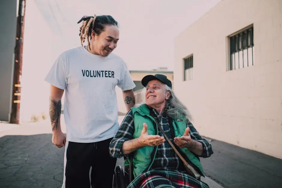 Smiling volunteer helping a senior man in a wheelchair outside on a sunny day.