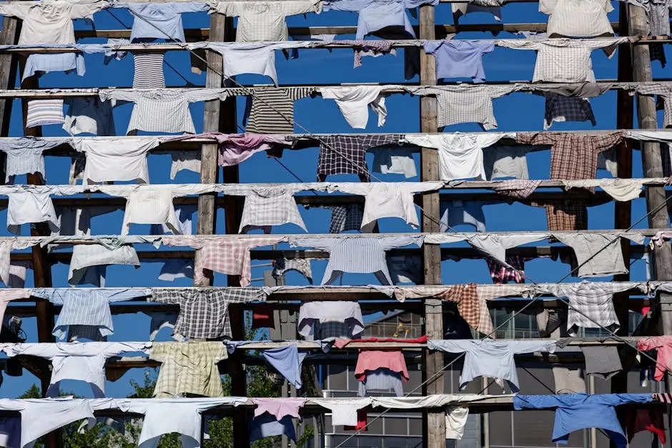 Vibrant shirts drying on clotheslines against a clear blue urban sky.