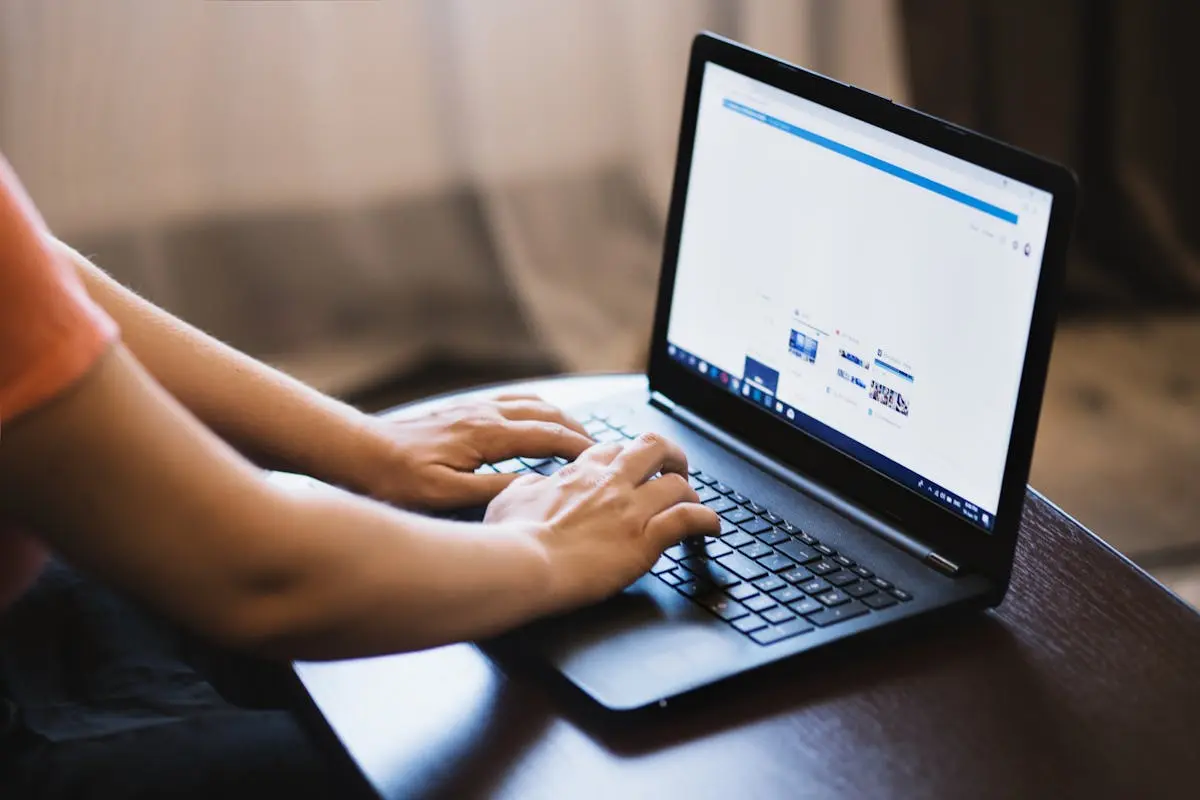 Close-up of outsourced cfo typing on a laptop indoors, showcasing technology use.