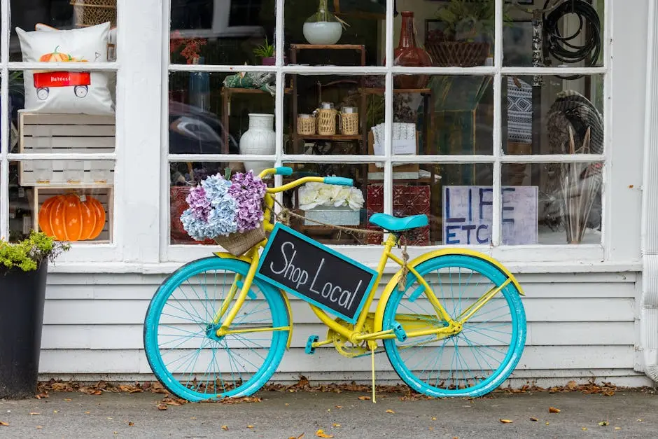 A colorful bicycle with flowers and &lsquo;Shop Local&rsquo; sign outside a store in Sudbury, MA.