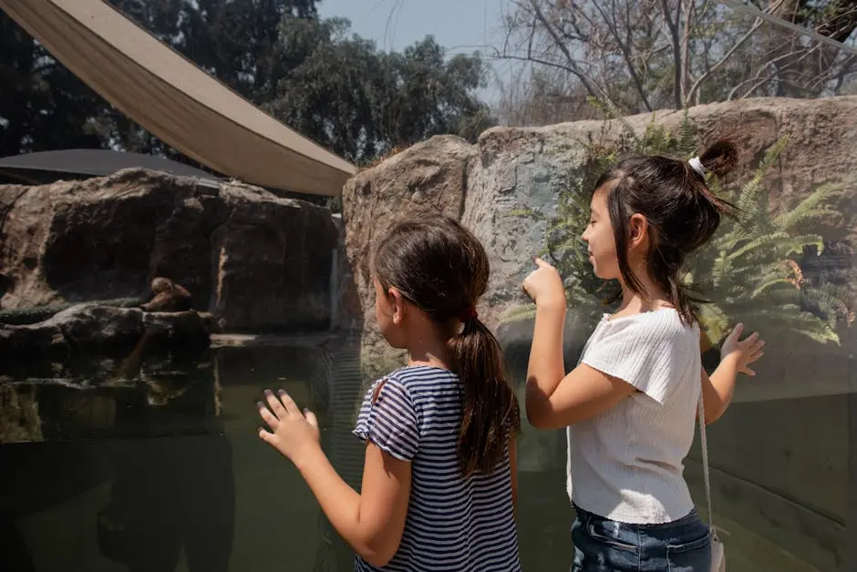 Two children observing an otter in a zoo aquarium through glass.