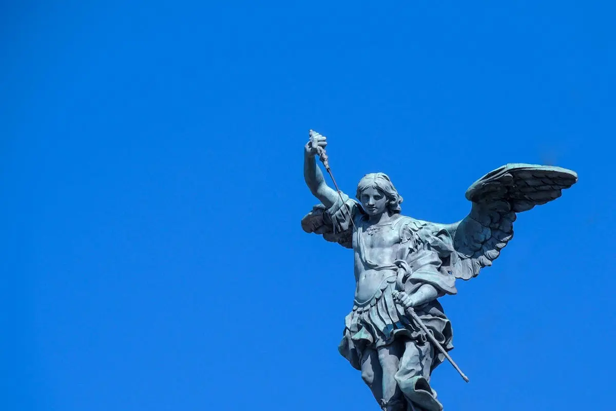 Stunning view of Archangel Michael statue in Rome with a bright blue sky backdrop.