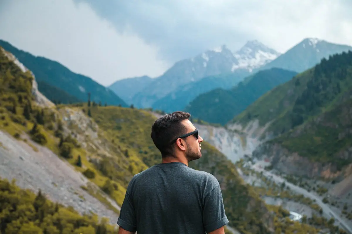 A man in sunglasses gazes at the breathtaking mountain landscape of Ulytau District, Kazakhstan.