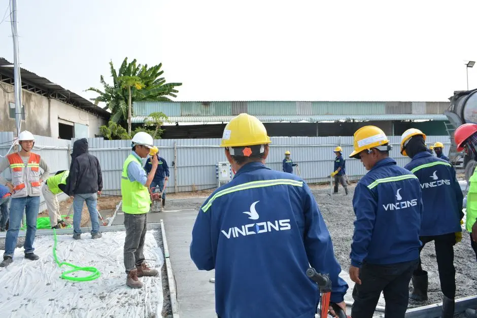 Group of construction workers wearing hard hats assessing a site outdoors.