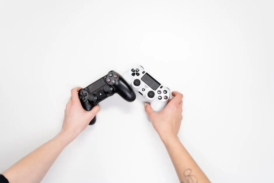 Top view of hands holding black and white game controllers on white background.