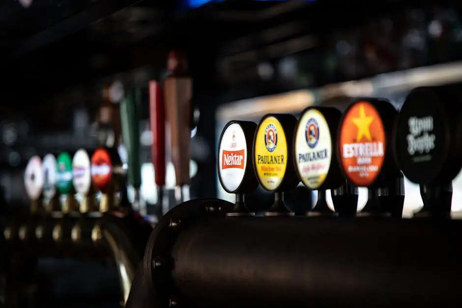 Close-up of assorted beer taps in a dimly lit bar, showcasing various brewery logos and selections.