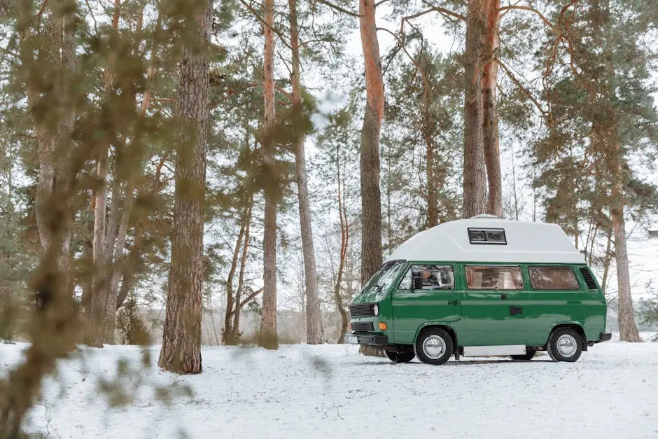 Explore the tranquil beauty of winter with a classic green camper van parked in a snowy forest.