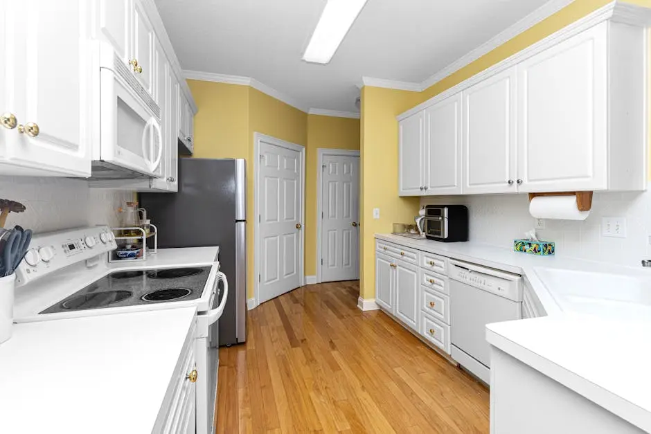 Spacious kitchen with white cabinets, wooden floor, and modern appliances.