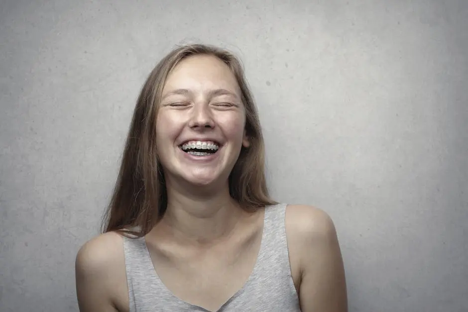 A cheerful woman with braces laughing joyfully in a casual portrait.