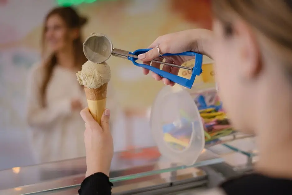 Close-up of a scoop of ice cream being served into a cone at a shop.