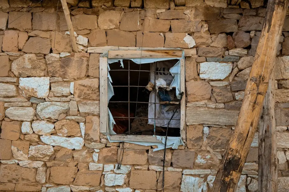 Aged stone wall with a wire-grilled broken window. Rustic and textured view.