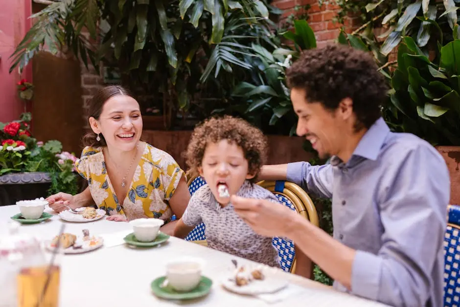Happy family sharing dessert together at an outdoor cafe with lush greenery.