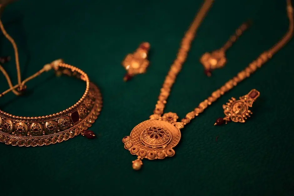 A stunning set of gold jewelry featuring a necklace and earrings on a textured green background.