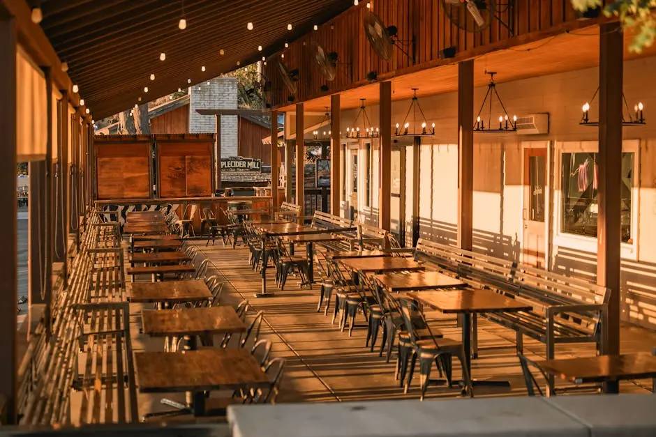 Warm and inviting outdoor patio area with wooden tables, chairs, and ambient lighting, perfect for dining.