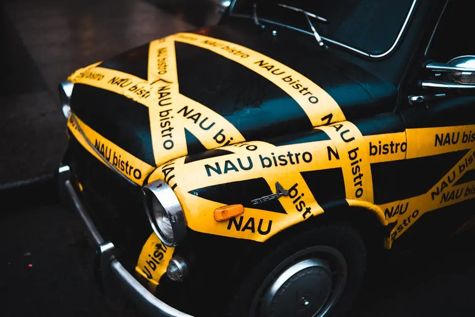 Retro car decorated with vibrant yellow advertising tape outdoors, unique urban presentation.