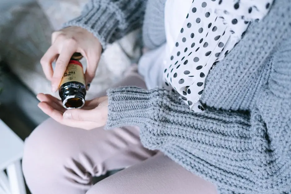 Close-up of a woman in cozy clothing holding a medicine bottle in her hands.