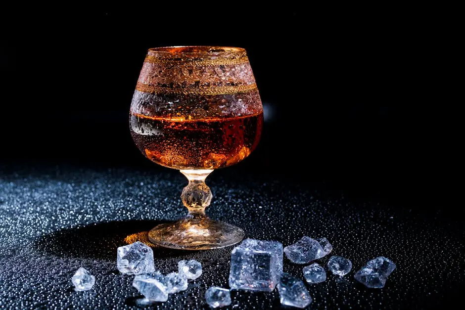 A luxury whiskey glass with ice cubes, elegantly displayed on a textured black surface, perfect for bar and drink themes.