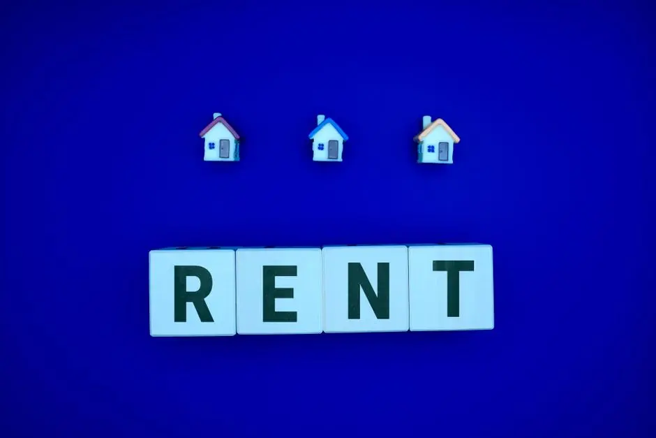 Miniature houses above letters spelling ‘RENT’ on a blue background, ideal for real estate themes.