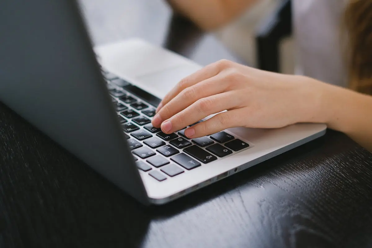Close-up of a hand typing on a laptop keyboard placed on a wooden desk. fractional coo
