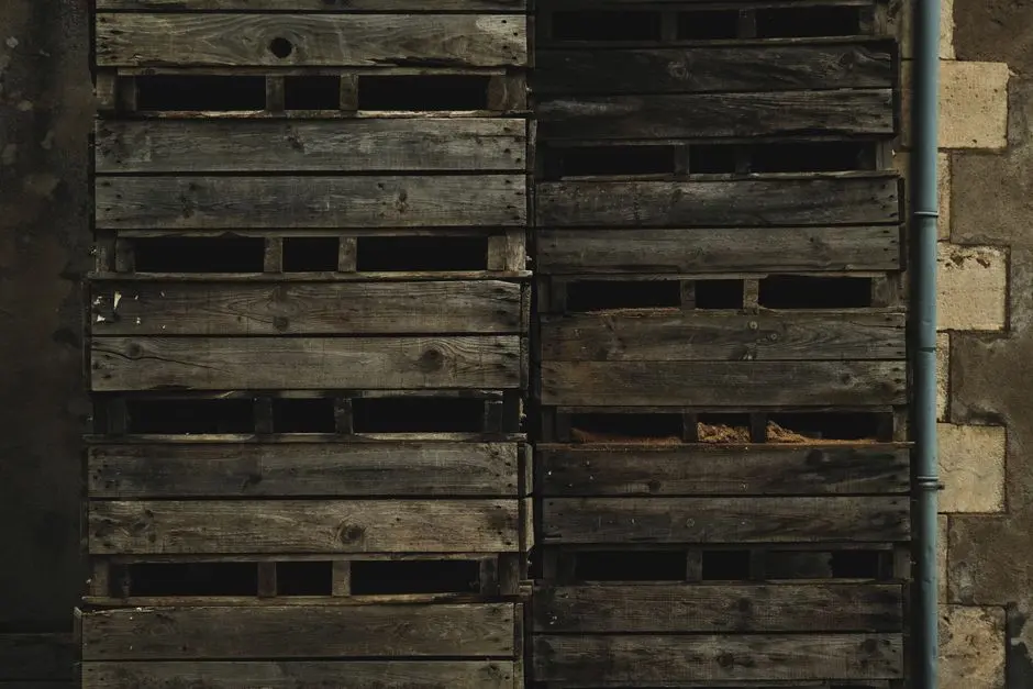 A textured arrangement of weathered wooden crates stacked against a rugged brick wall.
