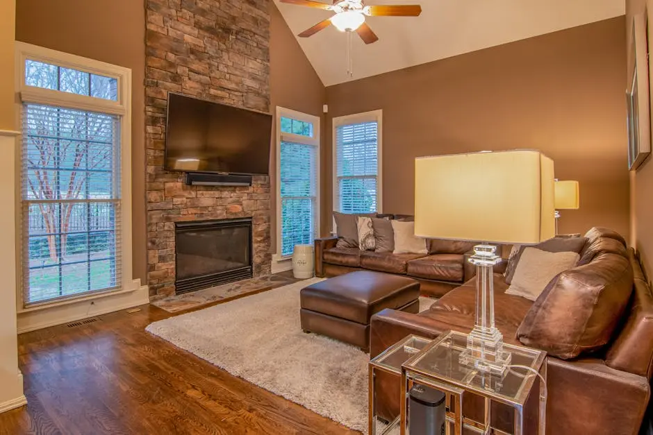 Warm and inviting living room featuring a stone fireplace, leather sofas, and ambient lighting.