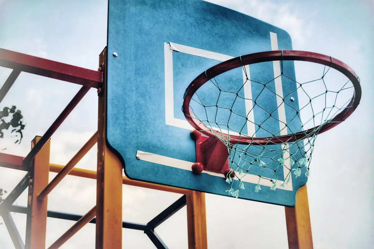 Close-up of an outdoor basketball hoop against a bright blue sky, highlighting sports equipment.