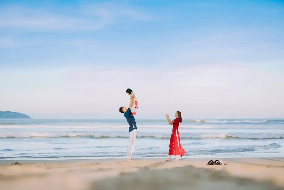 A joyful family enjoying a day at the beach with a father lifting his child towards the sky.
